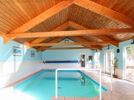 An indoor swimming pool with a wooden ceiling blue and white walls at Swallow Barn in Holton near Halesworth
