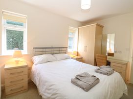 A bedroom with a double bed two nightstands with lamps a wardrobe a vanity table with a chair and two windows at Swallow Barn in Holton near Halesworth