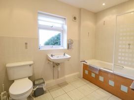 A bathroom with a toilet sink window and bathtub with glass panel at Swallow Barn in Holton near Halesworth