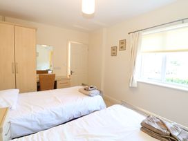 A bedroom with two single beds towels on beds a wardrobe a desk with chair and a window at Swallow Barn in Holton near Halesworth