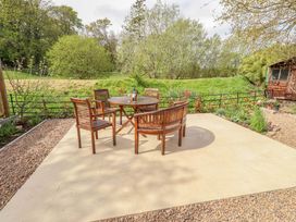 A garden with a wooden table and chairs at The Lodge in Powburn