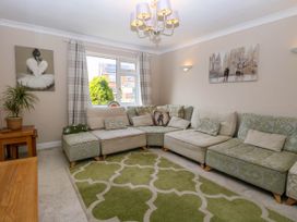 A living room with a sectional sofa and green patterned rug at 6 Barleycroft in Hemsby