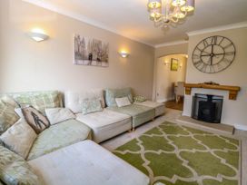 A living room with a sectional sofa a patterned rug a wall clock and a fireplace at 6 Barleycroft in Hemsby