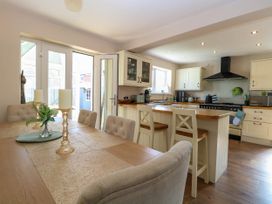 A kitchen and dining area with chairs a table candles and kitchen appliances at 6 Barleycroft in Hemsby