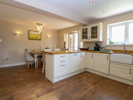 A kitchen with white cabinets and wooden countertops next to a dining area with a table and chairs at 6 Barleycroft in Hemsby