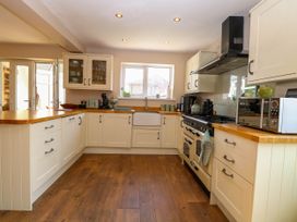A kitchen with cream cabinets wooden countertops a stove microwave and a window at 6 Barleycroft in Hemsby