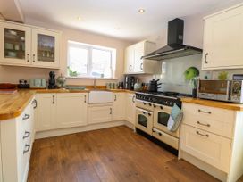 A kitchen with cream cabinets wooden countertops a stove a microwave and a window at 6 Barleycroft in Hemsby