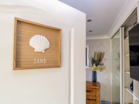 A room with a wooden chest of drawers with a vase of dried flowers a framed picture and a mirrored closet door at 6 Barleycroft in Hemsby