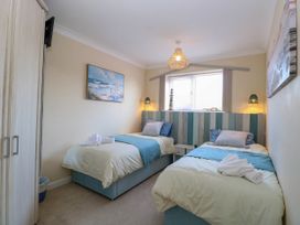 A bedroom with two single beds blue and white bed linens a wardrobe and wall art at 6 Barleycroft in Hemsby