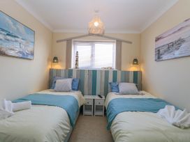 A bedroom with two single beds bedside table between them and coastal paintings on the walls at 6 Barleycroft in Hemsby