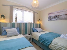 A bedroom with two single beds a small bedside table and a window at 6 Barleycroft in Hemsby