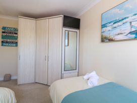 A bedroom with a wardrobe mirror television and two beds with towels at 6 Barleycroft in Hemsby