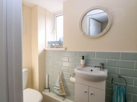 A bathroom with a toilet sink mirror towel and decorative items at 6 Barleycroft in Hemsby
