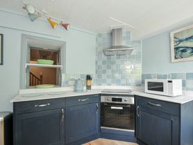 A kitchen with blue tiles and appliances at 2 Porthilly Cottages in Rock