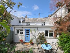 A garden with a house and seating area at 2 Porthilly Cottages in Rock