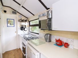 A compact kitchen with stove kettle microwave and red teapot at Captains Cabin Clarach Bay near Aberystwyth