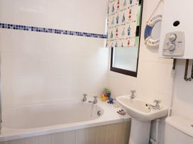 A bathroom with a bathtub sink toilet water heater and window with nautical-themed blind at Captains Cabin Clarach Bay near Aberystwyth
