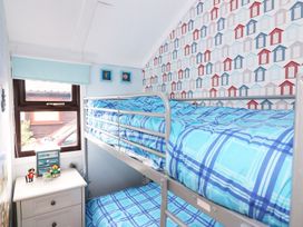 A small bedroom with a bunk bed and a chest of drawers near a window at Captains Cabin Clarach Bay near Aberystwyth