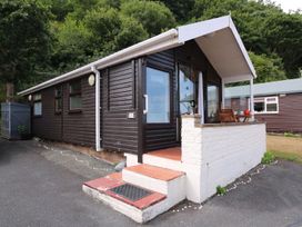 An exterior view of a wooden cabin with a small porch and steps at Captain's Cabin in Clarach Bay near Aberystwyth