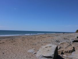A sandy and rocky beach with waves and a clear sky at Captains Cabin in Clarach Bay near Aberystwyth
