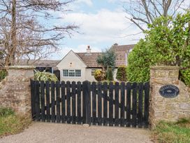A stone gate with a black wooden gate and a house behind the gate at Meadow Cottage in Staintondale near Cloughton