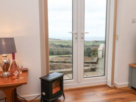 A room with double glass doors opening to a garden with a hill and sea view at Meadow Cottage in Staintondale near Cloughton