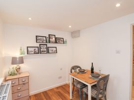 A dining area with a wooden table set for two and framed pictures on shelves at Meadow Cottage in Staintondale near Cloughton