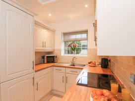 A kitchen with white cabinets a sink a microwave a fruit bowl and breakfast items at Meadow Cottage in Staintondale near Cloughton