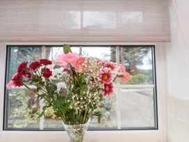 A vase with mixed flowers on a windowsill with a garden view at Meadow Cottage in Staintondale near Cloughton