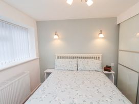 A bedroom with a double bed floral bedding two bedside tables and wall lights at Meadow Cottage in Staintondale near Cloughton