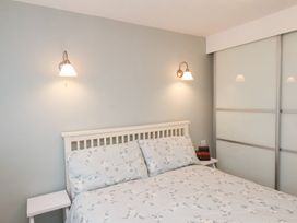 A bedroom with a bed with floral bedding two wall lights and sliding closet doors at Meadow Cottage Staintondale near Cloughton