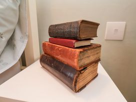 A stack of four old books on a white table near a light switch at Meadow Cottage in Staintondale near Cloughton