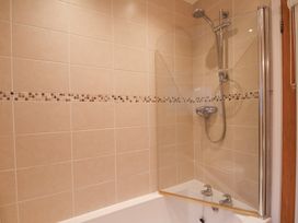 A bathroom with a tiled wall shower and bathtub with a glass screen at Meadow Cottage in Staintondale near Cloughton