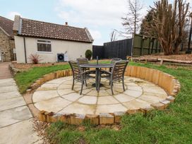 A backyard patio with a round table and four chairs surrounded by grass at Meadow Cottage in Staintondale near Cloughton