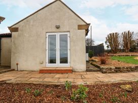 The exterior of a house with glass double doors opening onto a stone patio and landscaped garden at Meadow Cottage in Staintondale near Cloughton