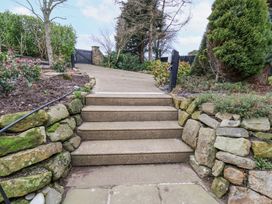 Stone steps leading up to a paved pathway with stone walls and plants on either side at Meadow Cottage in Staintondale near Cloughton