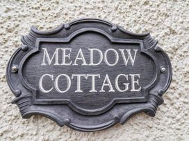 A decorative black house name plaque reading Meadow Cottage on a textured exterior wall at Meadow Cottage in Staintondale near Cloughton