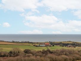 A rural landscape with fields trees and a farmhouse near the sea at Meadow Cottage in Staintondale near Cloughton