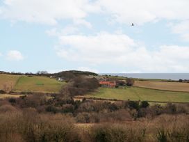 A rural landscape with fields trees and a building with a red roof at Meadow Cottage in Staintondale near Cloughton