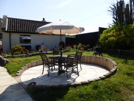 A garden with a table and chairs under an umbrella at Meadow Cottage in Staintondale near Cloughton