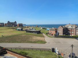 A coastal view with a grassy area, buildings, parking lot, and the sea at Mamoir's Place in Whitby
