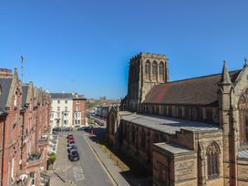 A street view with parked cars and a church building on the right side in Whitby