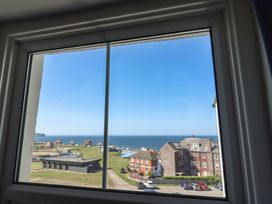 A coastal view from a window showing buildings a parking lot green lawn and the sea at Mamoir's Place in Whitby