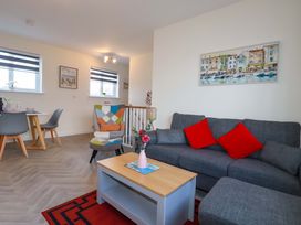 A living room with a sofa and dining area at 1 Vetch Avenue St Austell