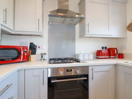 A kitchen with a stove and microwave at 1 Vetch Avenue in St Austell