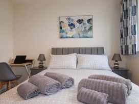 A bedroom with a bed, towels on it, and a desk at 1 Vetch Avenue in St Austell