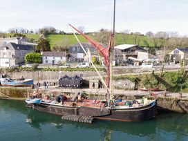 A boat docked at a waterfront with buildings and trees in the background at 1 Vetch Avenue St Austell