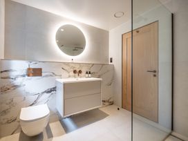 A bathroom with a sink, toilet, mirror, and shower at Deer Close in Coniston