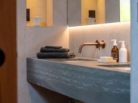 A bathroom sink with towels and bottles at Deer Close in Coniston