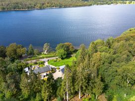 An aerial view of a house by a lake with a garden at Deer Close in Coniston